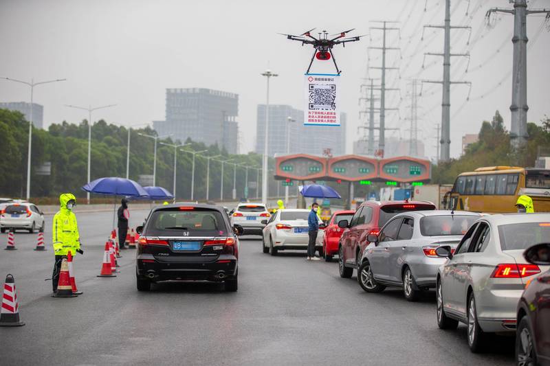 In this Tuesday, Feb. 11, 2020, photo released by China's Xinhua News Agency, a drone carries a QR code placard near an expressway toll station in Shenzhen in southern China's Guangdong Province. As a measure to help prevent and control novel coronavirus, an online register system for vehicles coming back to Shenzhen has been put into use since Feb. 8. To increase the efficiency, local police officers used drones to carry a QR code at the expressway exits for drivers to get registered with less contact with other people. (Lai Li/Xinhua via AP)