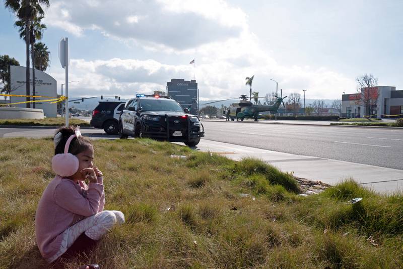 A young girl watches as police use armored vehicles to surround a white cargo van, believed to be connected to the Monterey Park mass shooting suspect. Reuters