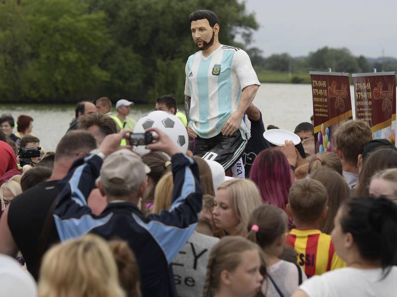 Visitors and children crowd around a birthday cake that includes a statue depicting Lionel Messi during a party organided by the town of Bronnitsy. AFP