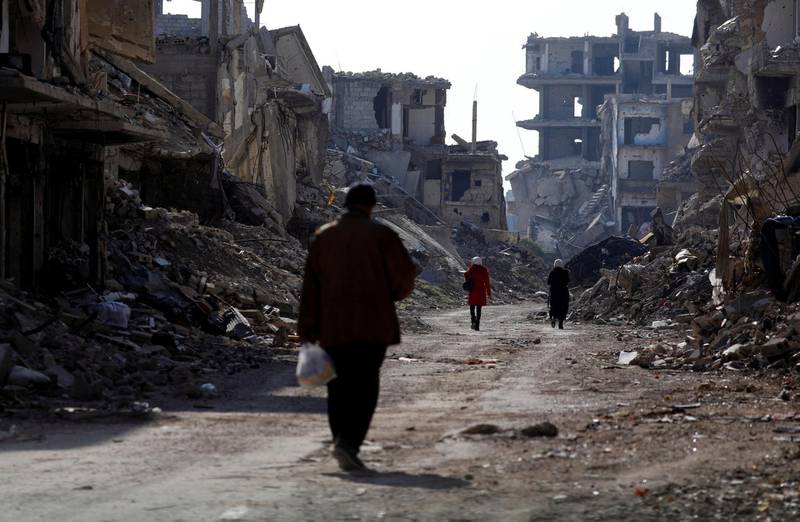 People walk past damaged buildings at the Yarmouk Palestinian refugee camp on the southern outskirts of Damascus, Syria December 2, 2020. Picture taken taken December 2, 2020. REUTERS/Omar Sanadiki