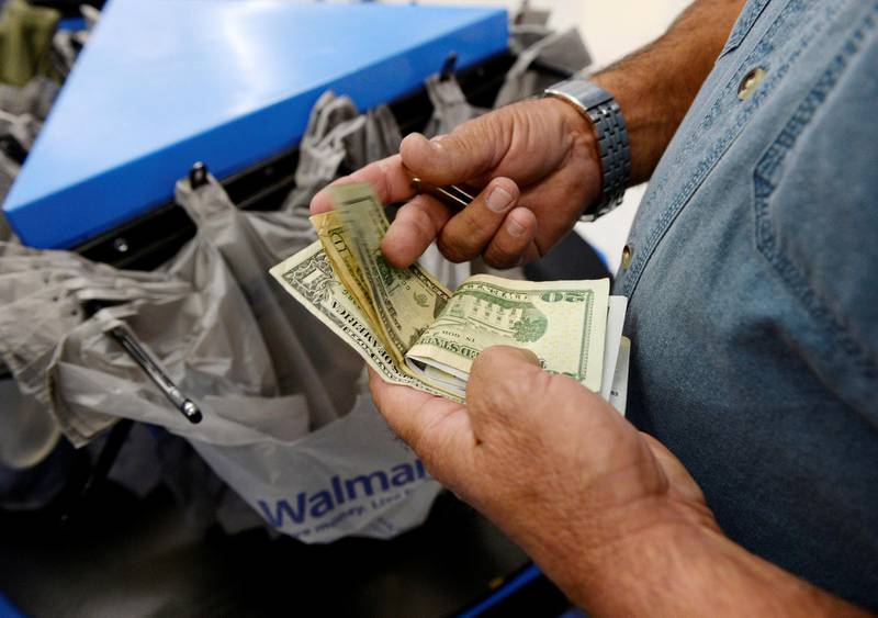 FILE PHOTO: A customer counts his cash at the checkout lane of a Walmart store in the Porter Ranch section of Los Angeles, California, U.S., November 26, 2013.  To match Insight USA-ECONOMY/CONSUMERS. REUTERS/Kevork Djansezian/File Photo