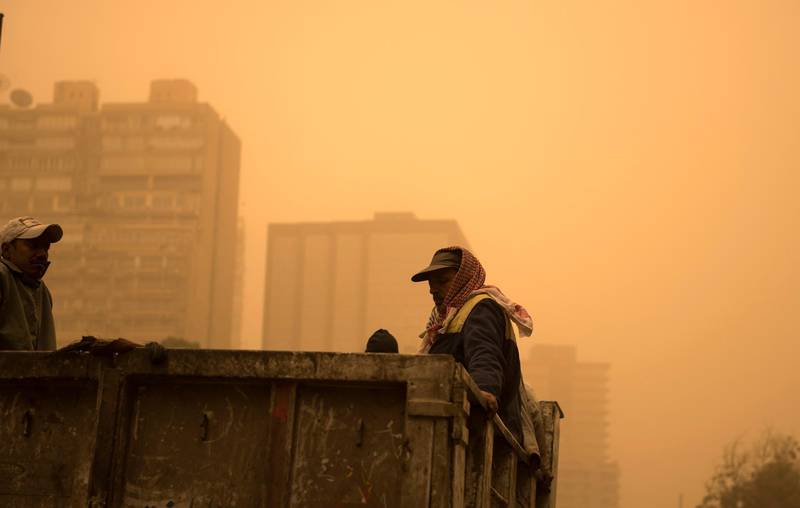 Waste collectors ride a truck during a sandstorm in Cairo, Egypt. EPA