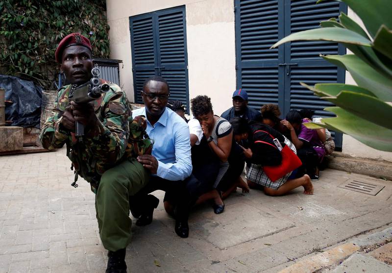 People are evacuated by a member of security forces at the scene where explosions and gunshots were heard at the Dusit hotel compound, in Nairobi, Kenya. Reuters