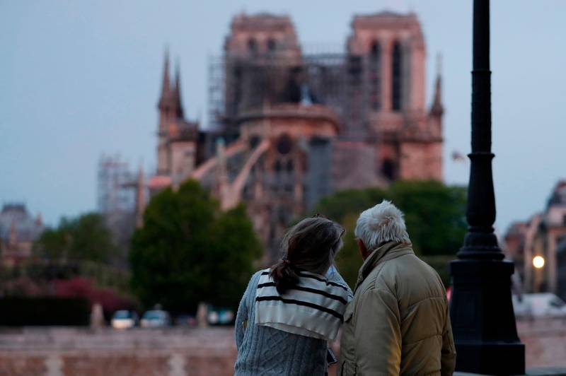 A couple looks on as firefighters race to save Notre-Dam. AFP