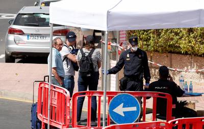 Tourists pass through a police checkpoint as they leave by foot the H10 Costa Adeje Palace hotel, which was placed on lockdown after four cases of the coronavirus were detected there, but others showed no symptom of illness, in Adeje, on the Spanish island of Tenerife, Spain. Reuters