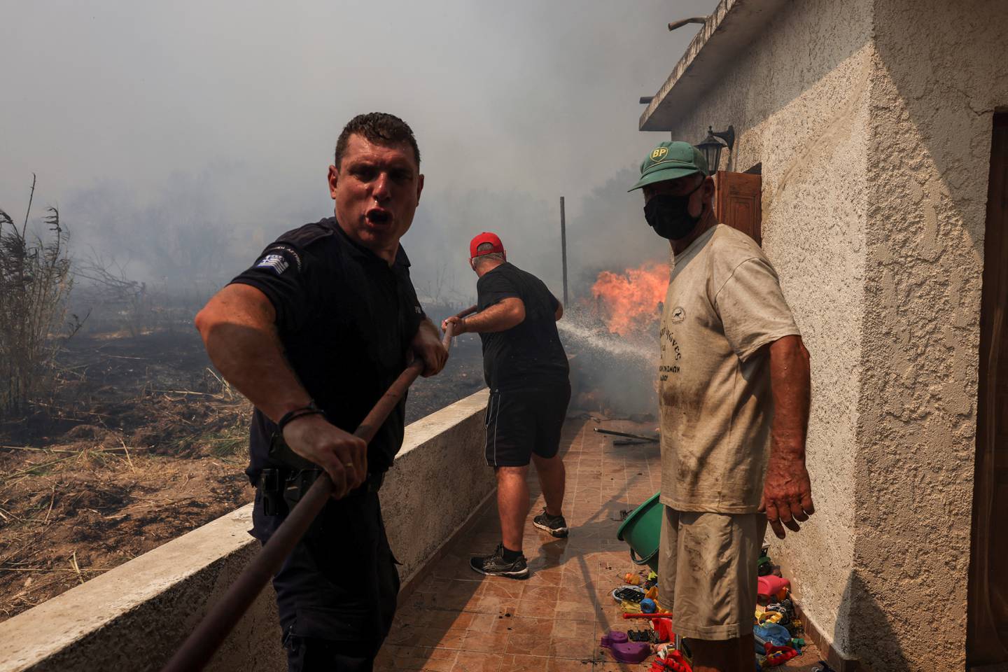 A police officer and residents try to fight back the flames in the village of Vatera, on the island of Lesbos, Greece. Reuters