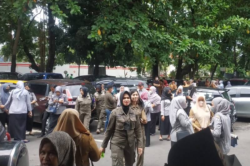 People wait outside a government building that was evacuated in Makassar, Indonesia, after the earthquake. AP