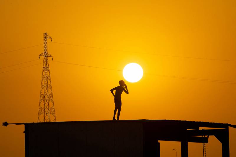 A boy prepares to jump off the roof of a structure to cool off in the waters of the Shatt Al Arab waterway.