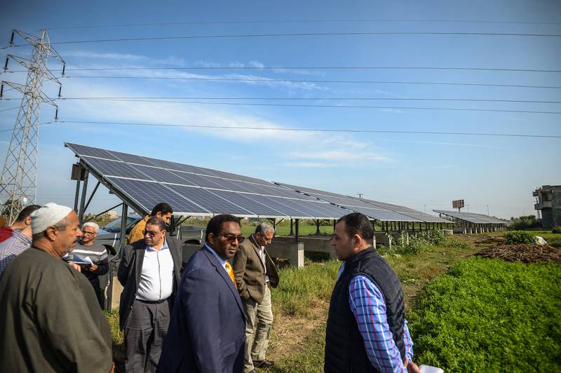 Hussein Gadain, centre, the UN's Food and Agriculture Organisation representative, checks solar panels with farmers in Kafr Al Dawar in northern Egypt's Nile Delta in 2018. Mohamed El Shahed / AFP