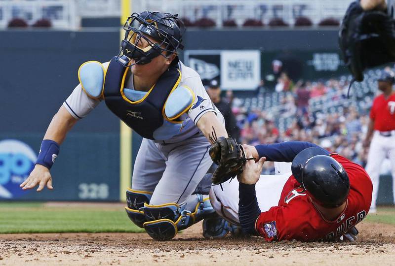 The face mask ofTampa Bay Rays catcher Hank Conger gets twisted as Minnesota Twins’ Joe Mauer beats the tag to score on a single by Trevor Plouffe in the third inning of a baseball game in Minneapolis. Jim Mone / AP photo