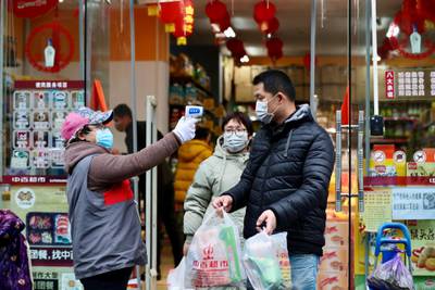 A worker measures body temperature of people leaving a supermarket in Qingshan district following an outbreak of the novel coronavirus in Wuhan, Hubei province, China. Reuters