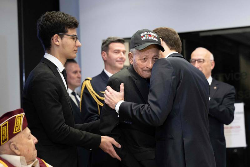 Mr Macron embraces veteran Buddy Reynolds after awarding him the Legion d'Honneur. Mr Reynolds, who is 101, attributes his long life to a dedication to 'service for others'. AFP

