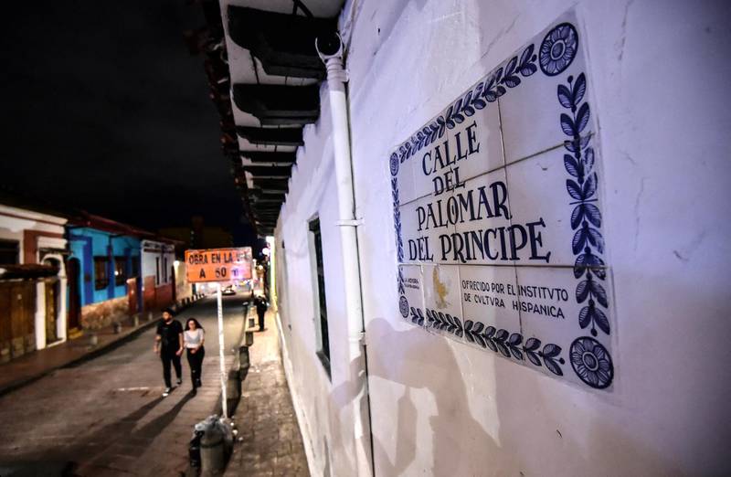 People walk at the historic district of La Candelaria, in Bogota at night, on October 31, 2018. - Legends and fantastic stories are back after being eclipsed for six decades of violence in Colombia. After the peace accord, some don't hesitate tracking down the ghosts of colonial Bogota. (Photo by Juan BARRETO / AFP)