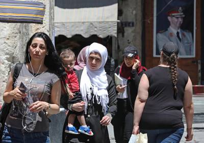 Syrians walk in old Damascus in front of a portrait of Syrian President Bashar Al Assad. AFP