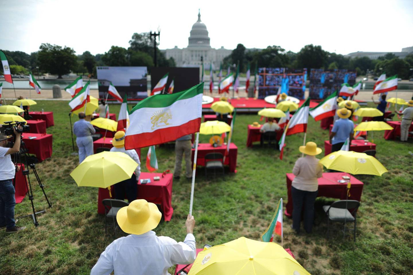 WASHINGTON, DC - JULY 17: Sitting at tables spaced out to reduce possible transmission of the novel coronavirus, Iranian-Americans gather under yellow umbrellas on the west side of the U.S. Capitol to demonstrate in support of a free Iran July 17, 2020 in Washington, DC. According to organizers, the demonstrators joined a global simulcast from 30,000 locations across 102 countries in support of a 'Free Iran.'   Chip Somodevilla/Getty Images/AFP
== FOR NEWSPAPERS, INTERNET, TELCOS & TELEVISION USE ONLY ==
