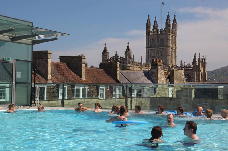 BATH, ENGLAND - APRIL 21:  Visitors enjoy the sunshine as they swim in the rooftop pool of the Thermae Bath Spa on April 21, 2009 in Bath, England. Despite the global economic downturn, visitors to the historic Unesco World Heritage city's attractions - including the 40million GBP Spa development and the only place in Britain where you can bathe in natural hot spring waters - have held steady, helped in part by the weakness of the pound encouraging foreigners to visit Britain, and British holidaymakers to stay at home. In 2007, nearly 4 million visitors earned the city's tourism industry 432 million GBP and early indicators suggest that the figures will be very similar for this year.  (Photo by Matt Cardy/Getty Images) *** Local Caption ***  WK30AU-TR-THARMAESPA02.jpg
