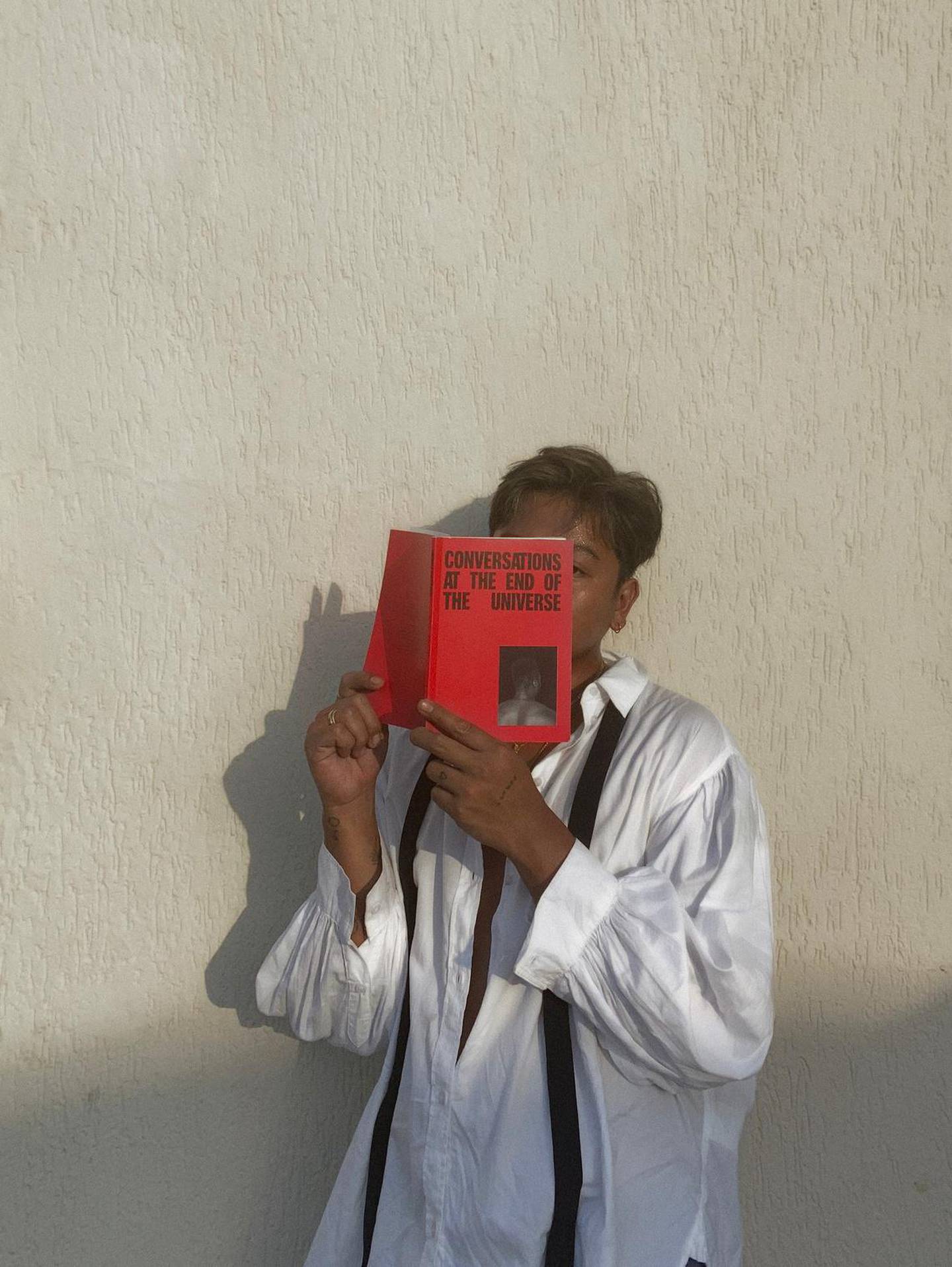 Dubai-born photographer Augustine Paredes hides behind his book 'Conversations at the End of the Universe'. Courtesy of the artist