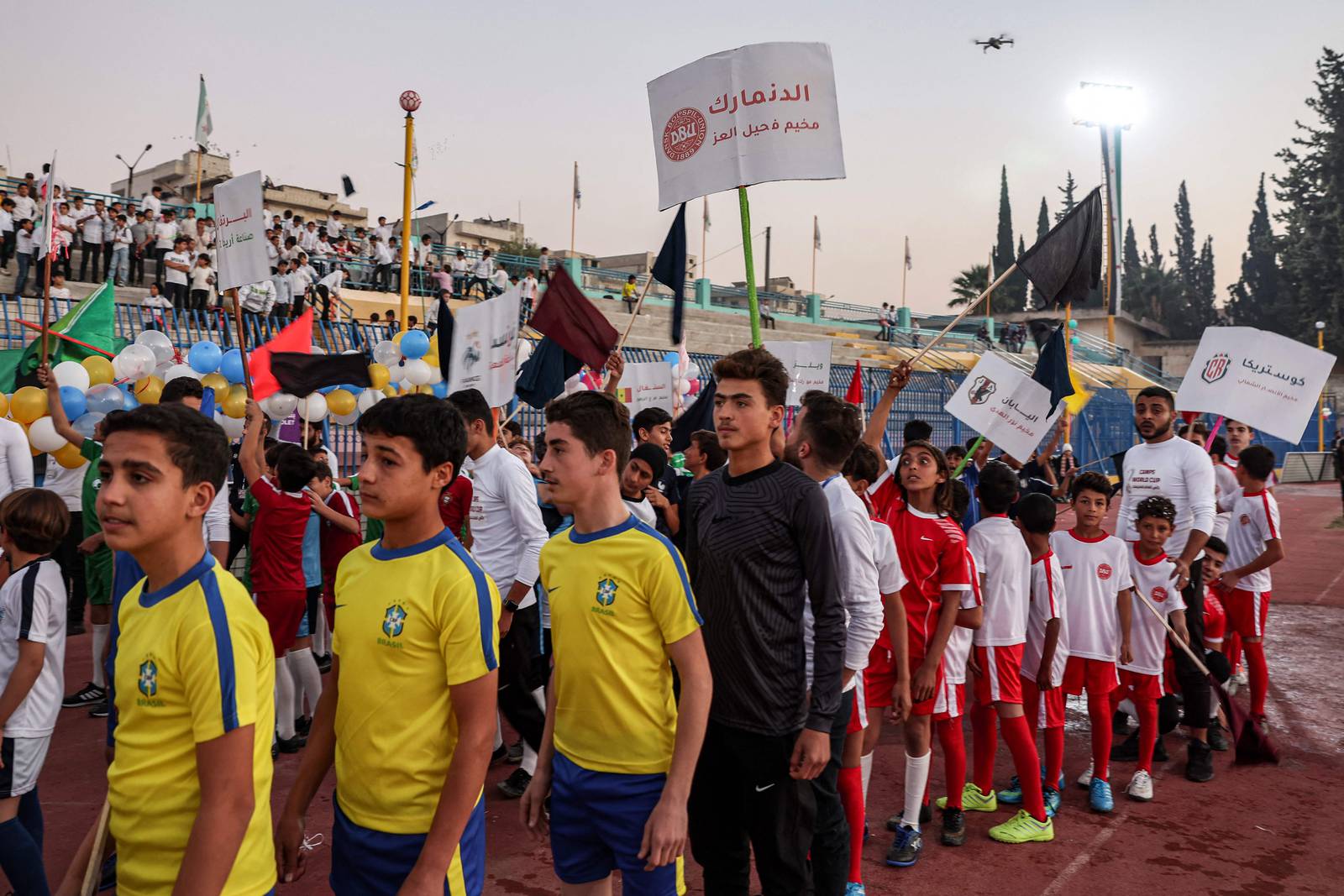 Des enfants enthousiastes participent à la cérémonie d'ouverture au stade municipal d'Idlib, dans le nord-ouest de la Syrie, portant les maillots des équipes de la Coupe du monde de cette année