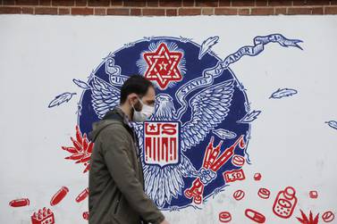 A man wearing a face mask walks past a wall of the former US Embassy with anti-America images on it, in Tehran, Iran November 8, 2020. Reuters