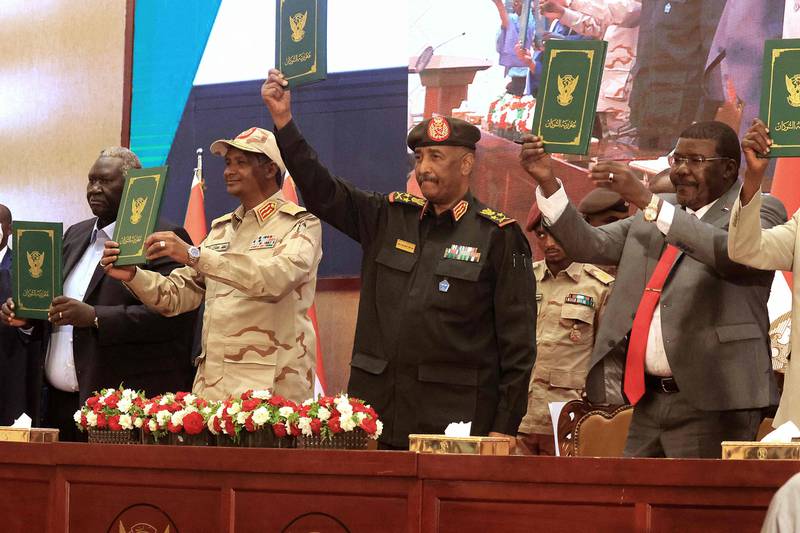 Sudan's Army chief Abdel Fattah al-Burhan and paramilitary commander Mohamed Hamdan Dagalo lift documents alongside civilian leaders following the signature of an initial deal aimed at ending the crisis. AFP