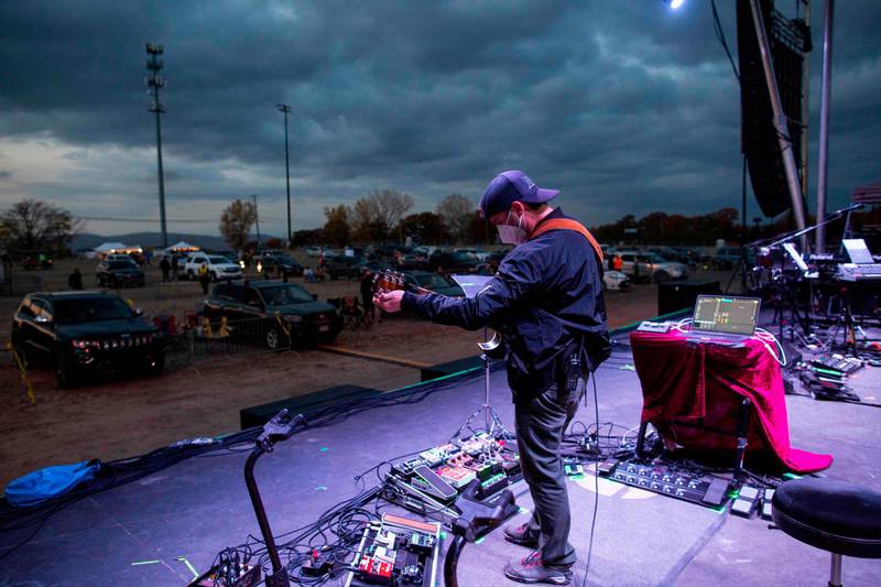 A musician from The Disco Biscuits plays on stage in front of lined-up cars. AFP
