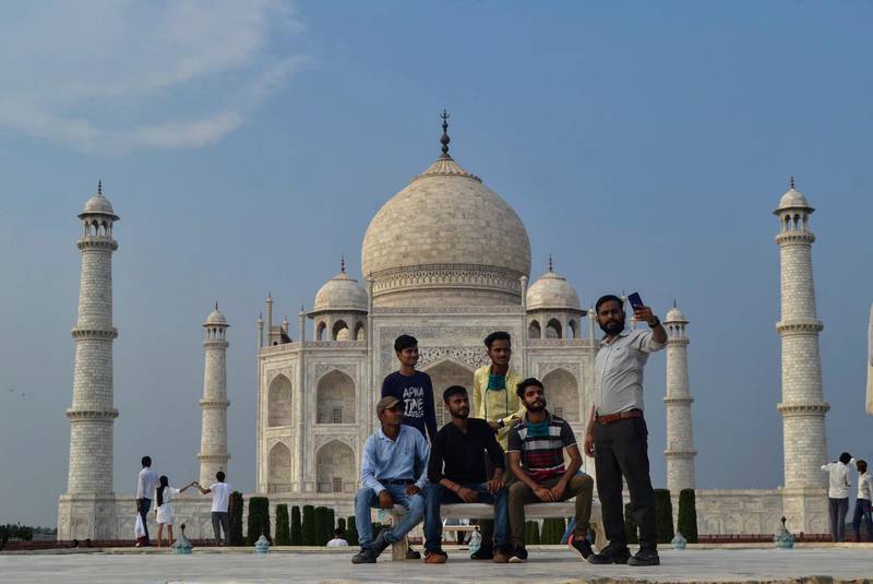 A group of Indian tourists pose for photographs in-front of the Taj Mahal monument that was reopened after being closed for more than six months due to the coronavirus pandemic in Agra, India, Monday, Sept.21, 2020. (AP Photo/Pawan Sharma)