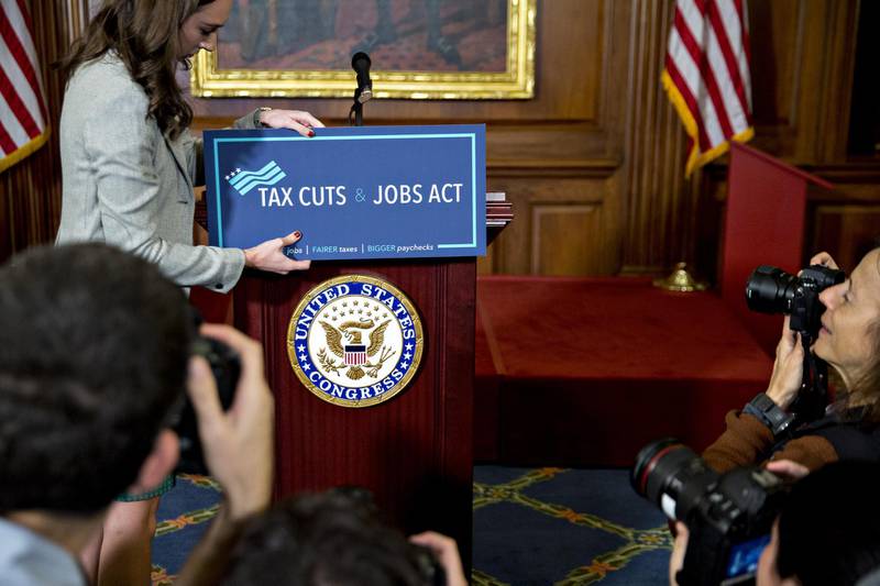 A staff member places a "Tax Cuts and Jobs Act" sign on a podium before a news conference with House Republican members after voting on the tax reform bill at the U.S. Capitol in Washington, D.C., U.S., on Thursday, Nov. 16, 2017. House Republicans passed their version of legislation to overhaul the U.S. tax code by slashing the corporate tax rate, lowering tax burdens for most individuals and adding an estimated $1.4 trillion to the federal deficit over the next decade. Photographer: Andrew Harrer/Bloomberg