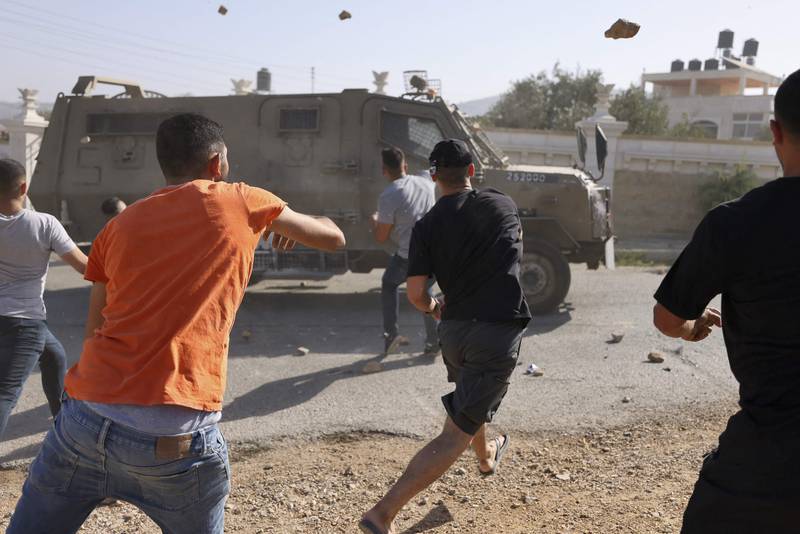 Palestinian youths throw rocks at an Israeli army vehicle in the town of Silwad, in the occupied West Bank, after a military operation in the region. AFP