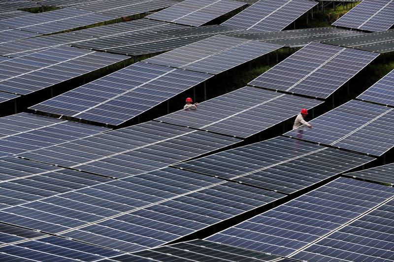 Workers check solar panels at a photovoltaic power station in Chongqing, China. Reuters