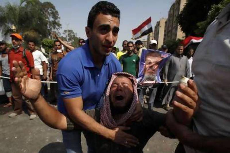 Members of the Muslim Brotherhood and supporters of deposed Egyptian president Mohammed Morsi grieve in front of soldiers outside the Republican Guard headquarters in Cairo.