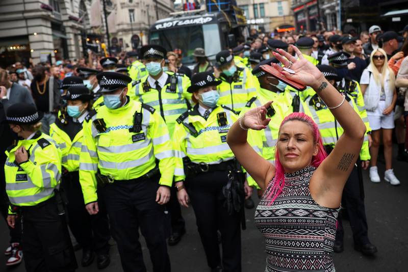 Police officers stand guard as demonstrators dance in London. Reuters