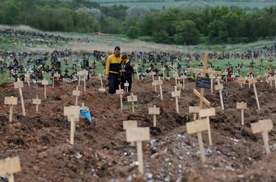 People stand amid newly-made graves at a cemetery in Staryi Krym outside Mariupol on May 22. Reuters