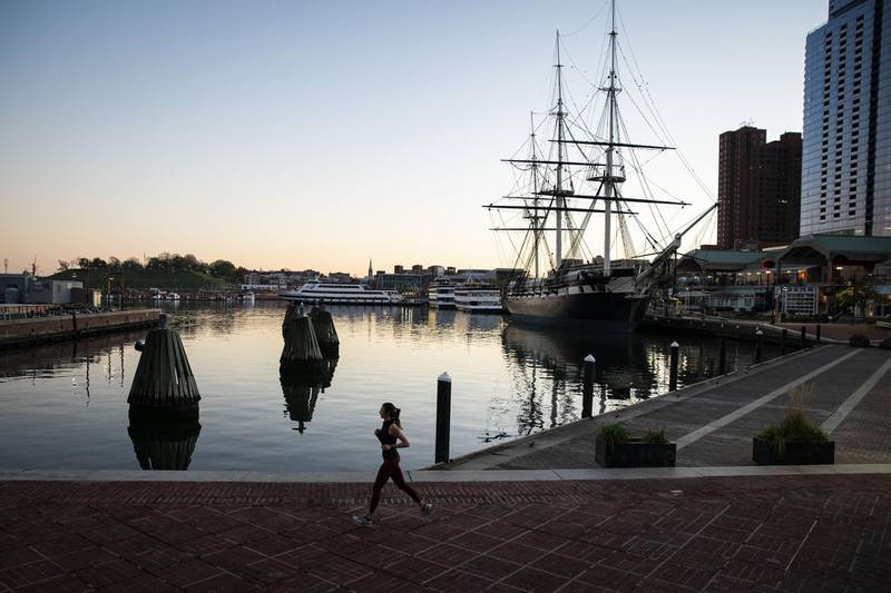 A runner passes through Inner Harbor in Baltimore, Maryland, US. Coronavirus infections continue to rise in the greater Washington region, with more than 5,000 new cases reported on Thursday, a daily record. Bloomberg