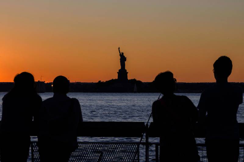 The Statue of Liberty is visible in the distance as people watch the sunset in New York City. AFP
