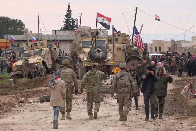 Russians, Syrians and others gather next to an American military convoy stuck in the village of Khirbet Ammu, east of Qamishli city, on February 12, 2020. AP Photo