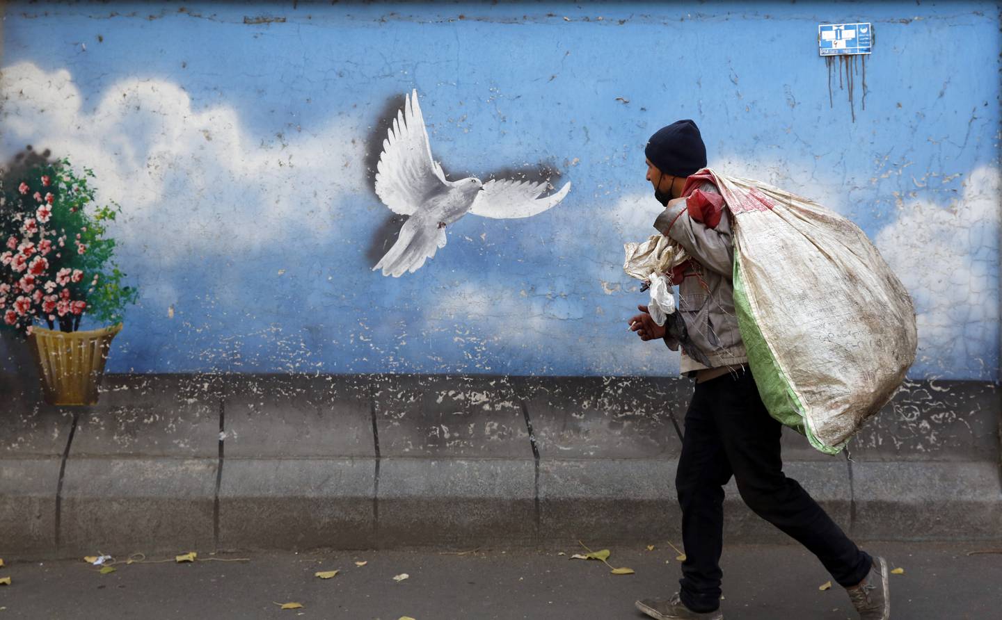 An Iranian vendor walks past a mural depicting a flying dove in a street of Tehran, Iran,  November 29. EPA