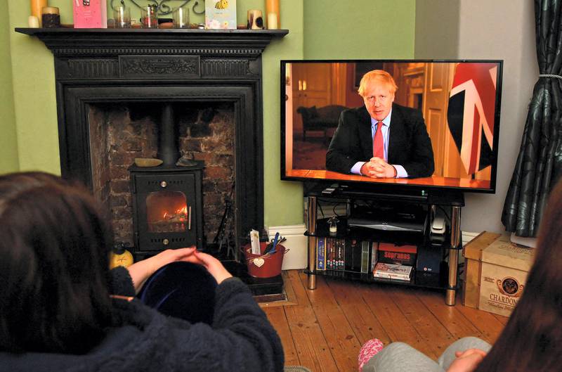 Members of a family listen as Britain's Prime Minister Boris Johnson makes a televised address to the nation from inside 10 Downing Street in London, with the latest instructions to stay at home to help contain the Covid-19 pandemic, from a house in Liverpool, north west England on March 23, 2020. - Britain on Monday ordered a three-week lockdown to tackle the spread of coronavirus, shutting "non-essential" shops and services, and banning gatherings of more than two people. "Stay at home," Prime Minister Boris Johnson said in a televised address to the nation, as he unveiled unprecedented peacetime measures after the death toll climbed to 335. (Photo by Paul ELLIS / AFP)