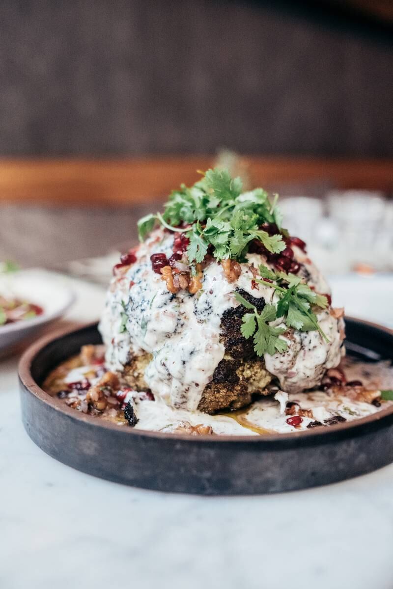 Roasted head of cauliflower served in spiced butter, yoghurt tahini tartare, walnuts and pomegranate, at Baron. Photo: Gates Hospitality