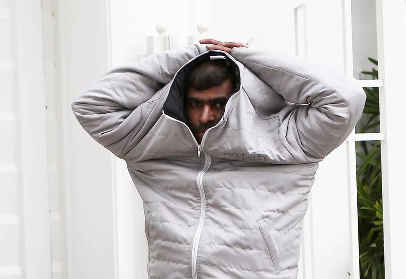 A man covers himself with his jacket during the rain in Abu Dhabi. Pawan Singh / The National