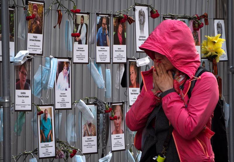 A woman reacts as she walks past portraits of St Petersburg's medical workers who have died from coronavirus, hanging at a unofficial memorial in front of the local health department, Russia. AP Photo