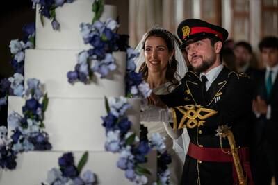 Prince Hussein and Princess Rajwa use a ceremonial sword to cut their cake.  Reuters