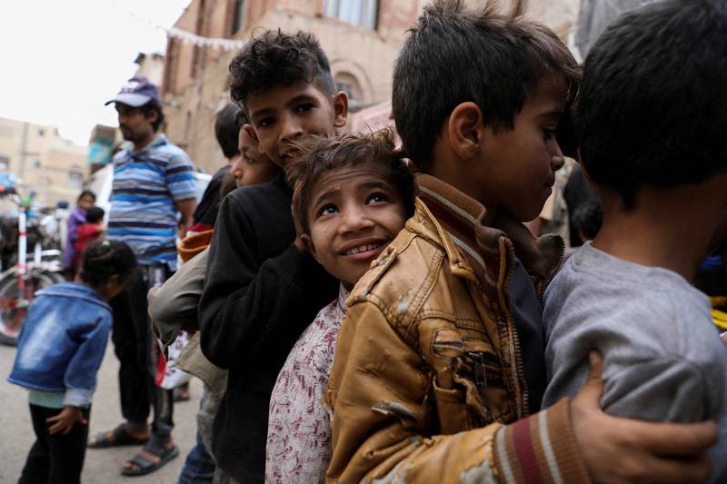 Boys stand in line as they wait to receive meals from a charity kitchen in Sanaa.