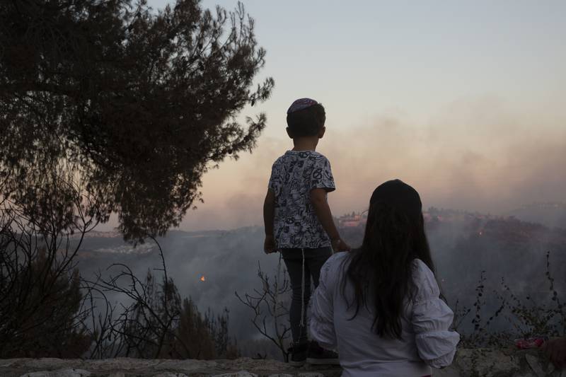 An Israeli mother and son watch as firefighters battle wildfires for the second day near Shoresh, on the outskirts of Jerusalem.