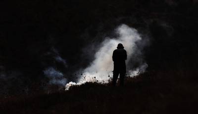 A Palestinian protester seeks cover from a tear gas grenade during clashes after a demonstration against Israel's settlements in the village of Asera near the northern West Bank city of Nablus. EPA