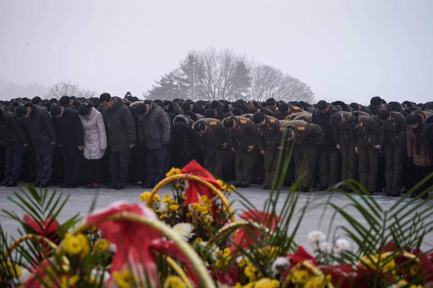 Pyongyang residents bow before the statues of late North Korean leaders Kim Il Sung and Kim Jong Il during National Memorial Day on Mansu Hill in Pyongyang on December 17, 2018. North Korea is marking the seventh anniversary of the death of Kim Jong Il. / AFP / KIM Won Jin
