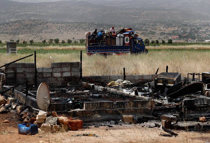 A Syrian family with their belongings ride past a burnt tent in a truck as they evacuate an informal refugee camp after a fight broke out last week between camp residents and Lebanese firefighters who arrived to put out a fire, in Deir Al-Ahmar, east Lebanon, Sunday, June 9, 2019. Dozens of Syrian refugees have dismantled their tents in a camp they lived in for years in eastern Lebanon after authorities ordered their evacuation following a brawl with locals. Lebanon hosts over 1 million Syrian refugees who fled the war next door since 2011, overwhelming the country of nearly 5 million. (AP Photo/Hussein Malla)
