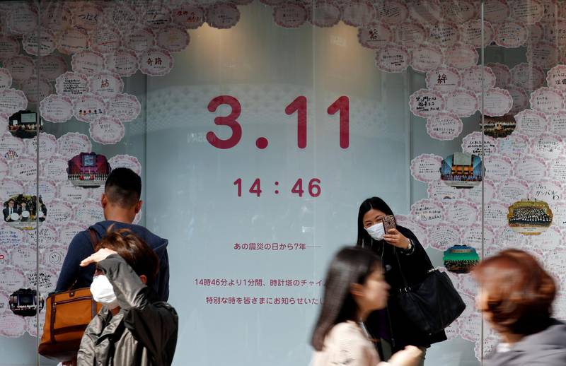 People walk next to a board with messages mourning the victims of the March 11, 2011 earthquake and tsunami disaster at Ginza shopping district in Tokyo, Japan, on March 11, 2018, to mark the seven-year anniversary of the earthquake and tsunami that killed thousands and set off a nuclear crisis. Issei Kato / Reuters