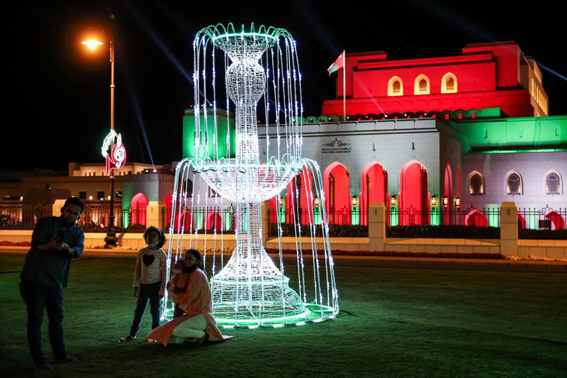 Indian residents of Oman pose for a picture on the lawn before the Royal Opera House Muscat in Oman's capital, lit up with the national colours on the occasion of the Omani national day.  AFP