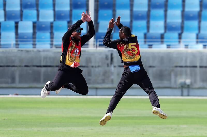 PNG's Sema Kamea, right, celebrates after taking the wicket of UAE batter Aryan Lakra for five.