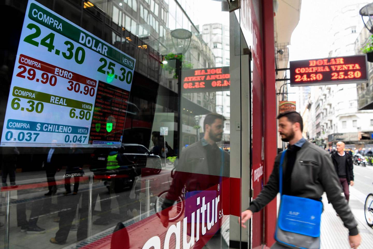 Currency exchange values are displayed in the buy-sell board of a bureau de exchange in Buenos Aires, on May 14, 2018. Argentina's peso plummeted by more than 6 percent on Monday, sparking new inflation fears for Latin America's third-largest economy. The currency fell 6.6 percent to trade at 25.20 against the dollar as markets opened. / AFP / Eitan ABRAMOVICH
